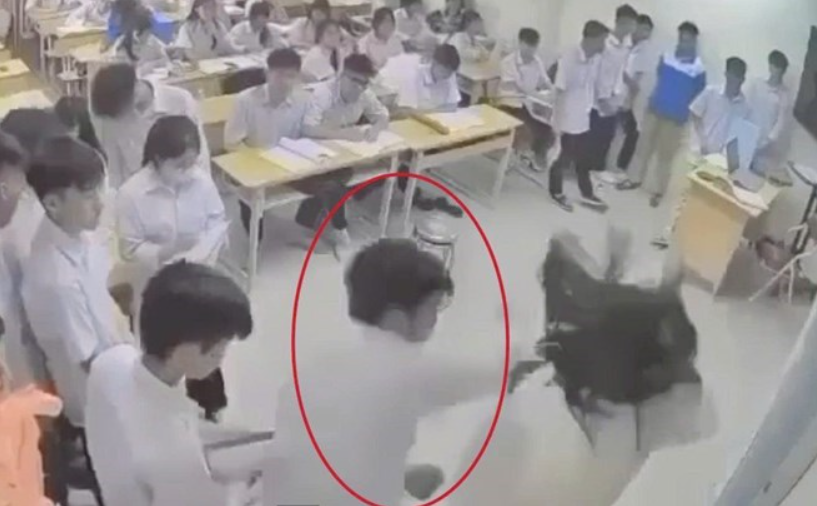 Hình ảnh nam sinh (khoanh đỏ) có hành vi hành hung nữ giáo viên ngay trên bục giảng. Ảnh: Cắt từ clip