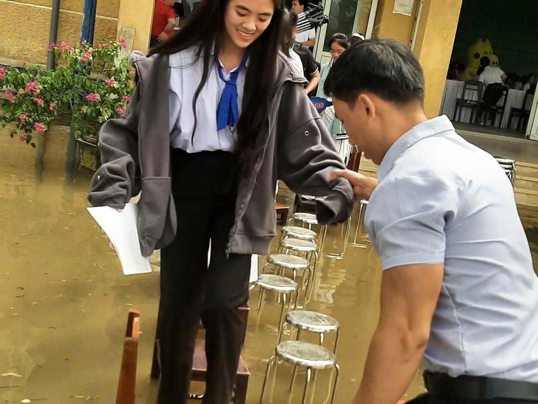 Giáo viên xếp ghế làm cầu, dắt học trò vào lễ tổng kết giữa sân trường ngập nước