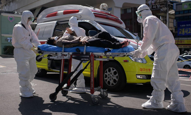 Nhân viên y tế đưa một bệnh nhân vào nhập viện tại Daegu hôm 12/3. Ảnh: AFP.