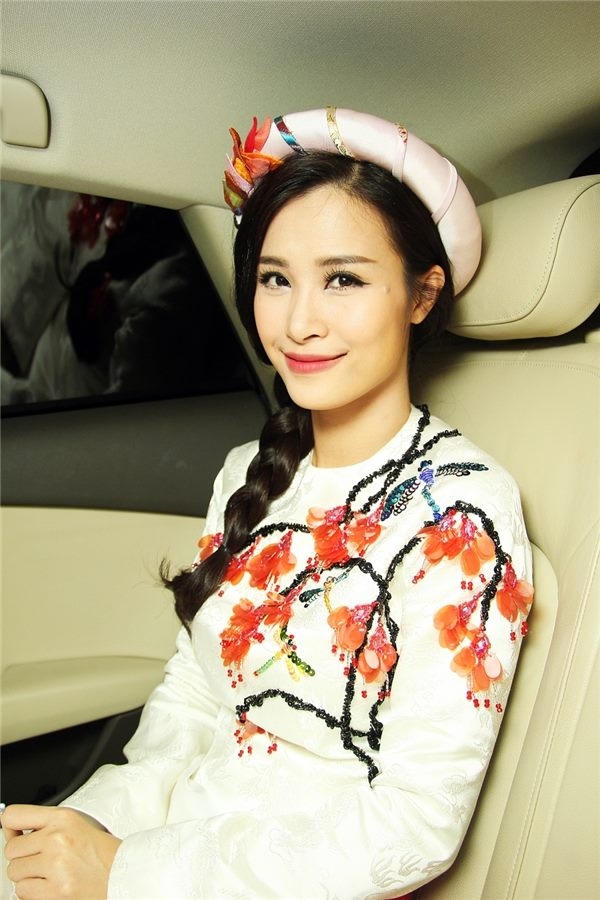 Trên nền trắng, bộ trang phục của Đông Nhi được tạo điểm nhấn bằng họa tiết hoa đào đính kết bằng cườm, đá. Chiếc mấn kết hợp đồng điệu về màu sắc, chi tiết với trang phục.