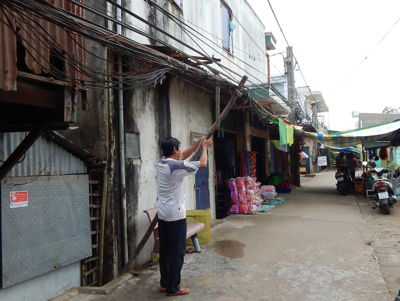 Trụ điện giữa lối đi, dây lòng thòng trên đầu người