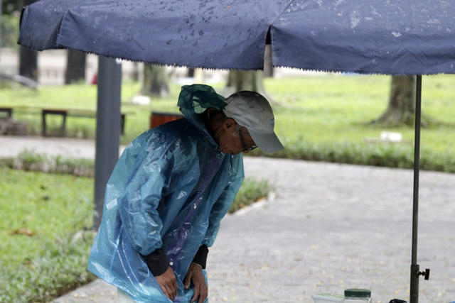 Một cụ già mặc thêm áo mưa để chống rét.