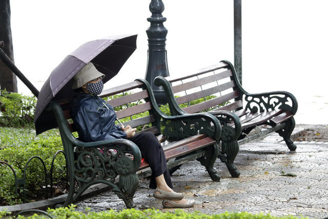  Một cụ già mặc áo ấm ngồi nghỉ ven bờ hồ Hoàn Kiếm. 