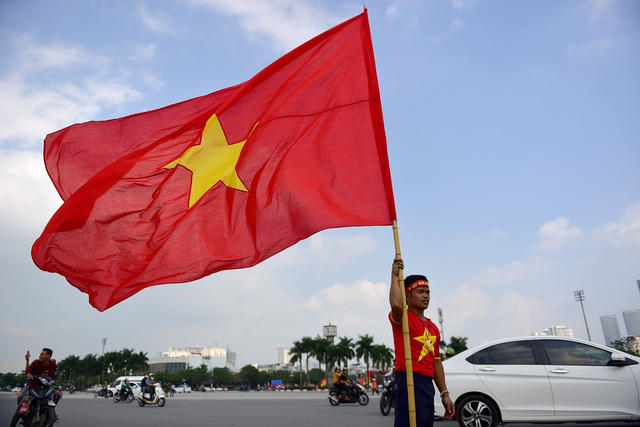 Một cổ động viên chuẩn bị lá cờ Tổ quốc lớn để tham gia diễu hành cùng đoàn.