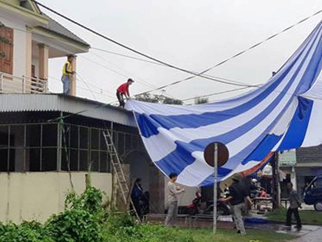  Nhiều người đội mưa để căng bạt phục vụ xem trận chung kết. 