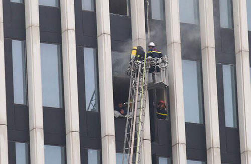 Cảnh sát cứu hỏa đập kính để tiếp cạn đám cháy. Ảnh: Gia Chính