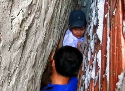 Cháu bé 8 tuổi được cảnh sát phá tường giải cứu. Ảnh: Thanh Liêm