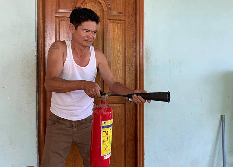 Ông Ngà và chiếc bình chữa cháy dùng chống trả nhóm tấn công. Ảnh: Minh Tâm.