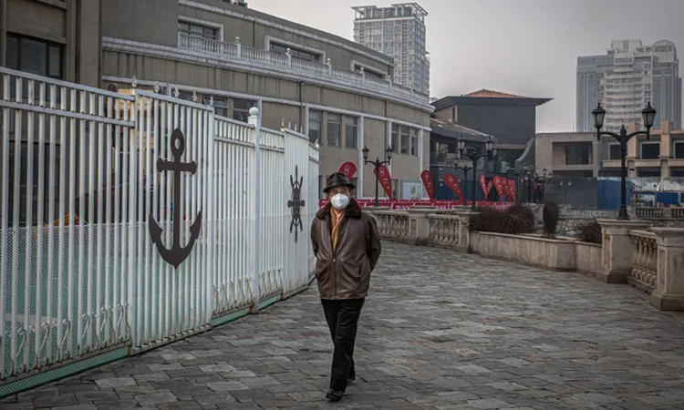 Người đàn ông đeo khẩu trang đi bộ bên ngoài trung tâm mua sắm Solana vắng tanh ở Bắc Kinh hôm 12/2. Ảnh: Washington Post.