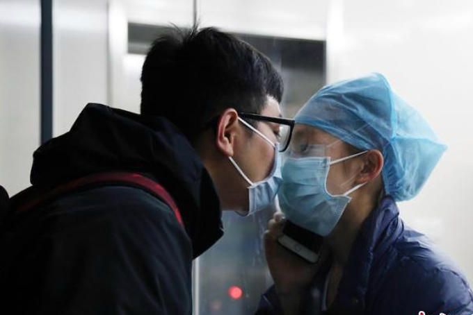Y tá Chen Ying và bạn trai Huang Qianrui hôn nhau qua tấm kính cách ly ở bệnh viện Đại học Y Khoa tỉnh Chiết Giang. Ảnh: CNNews.