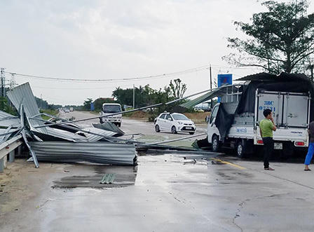 Lốc xoáy bốc mái tôn trùm lên xe tải đang chạy trên Quốc lộ