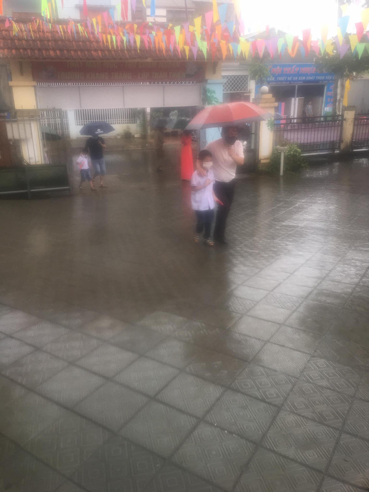 Học sinh đội mưa, đeo kính chắn giọt bắn dự lễ khai giảng