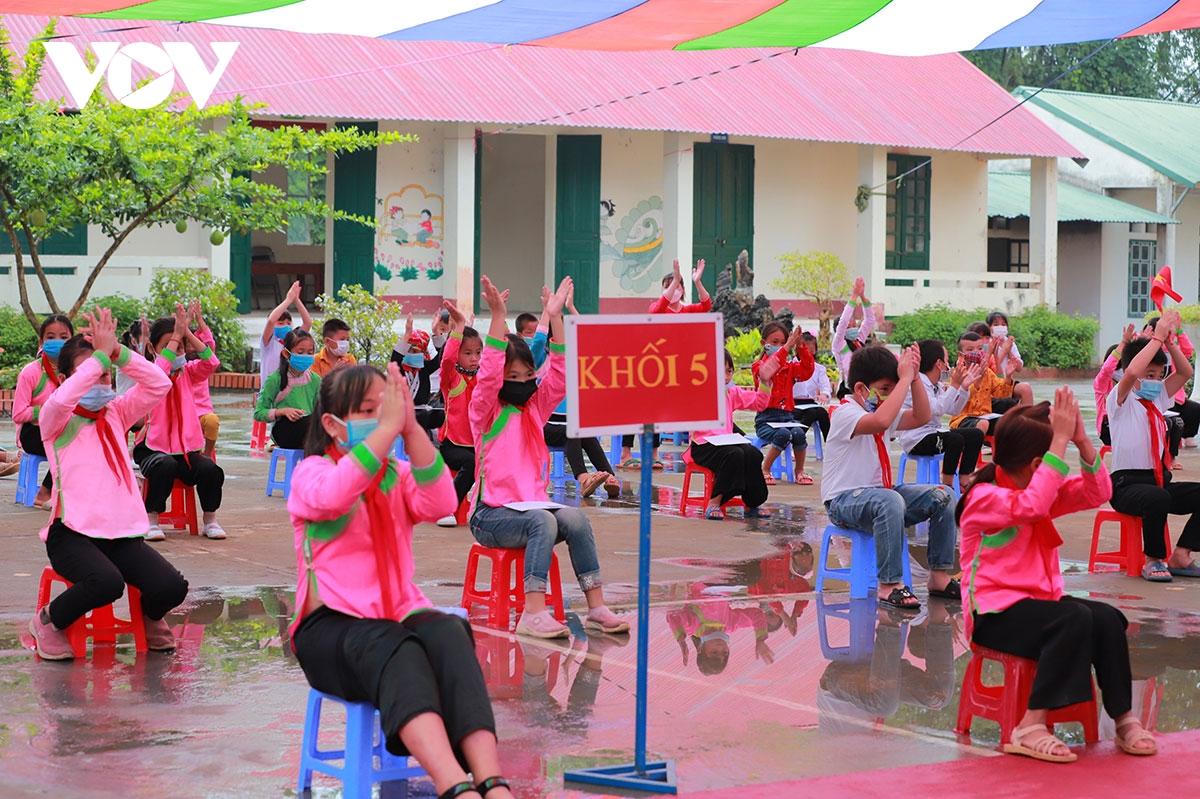 Học sinh đội mưa, đeo kính chắn giọt bắn dự lễ khai giảng