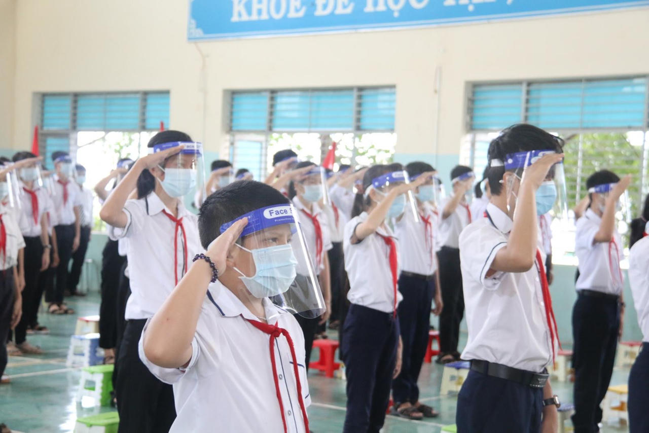 Học sinh đội mưa, đeo kính chắn giọt bắn dự lễ khai giảng