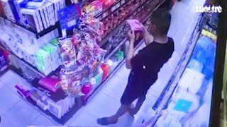 Người đàn ông áo đen bôi nước bọt lên hàng hóa trong một siêu thị