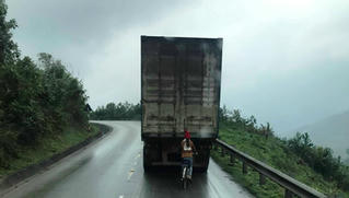 Kinh hãi nữ sinh đi xe đạp bám đuôi ô tô container khi vượt đèo