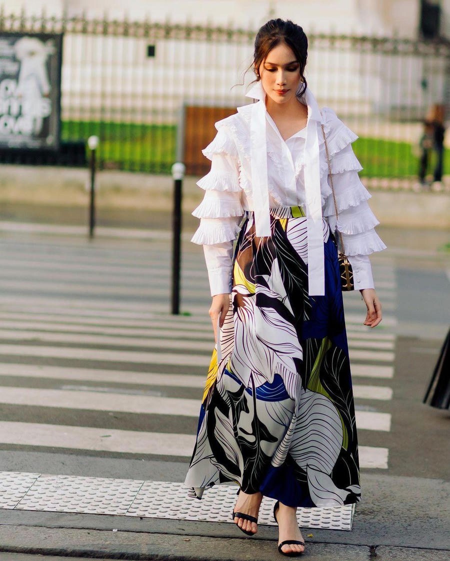 Họa tiết điểm nhấn được tập trung ở phần thân váy, sử dụng các màu sắc và các nét uốn lượn theo hình cánh hoa. Kết hợp là chiếc áo sơ mi trắng với thiết kế vành xếp tầng ở phần tay.