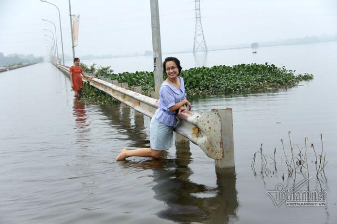 Tạo dáng chụp ảnh bên tỉnh lộ ngập nước