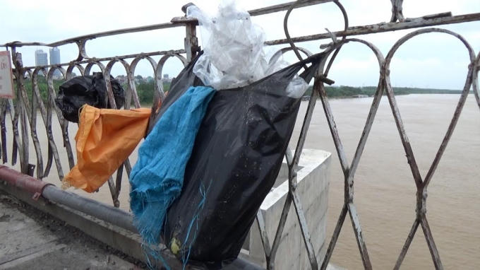 Sau khi xả tro vàng mã xuống sông, người dân vô tư buộc lại túi ni lông trên lan can thành cầu Long Biên.