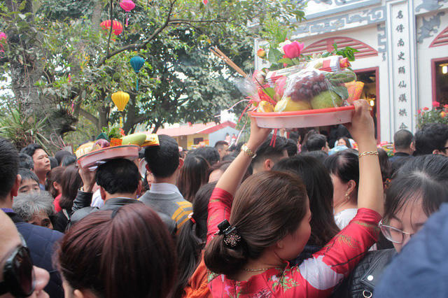 Một người phụ nữ khó nhọc bê đồ lễ lên đầu, di chuyển chậm chạp trong biển người.