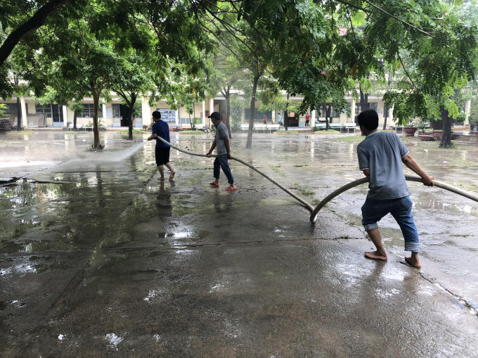 Nhà trường phải sử dụng vòi phun chữa cháy để làm sạch lớp bùn dày bám lại trên mặt sân cho kịp buổi chiều học sinh đi học trở lại