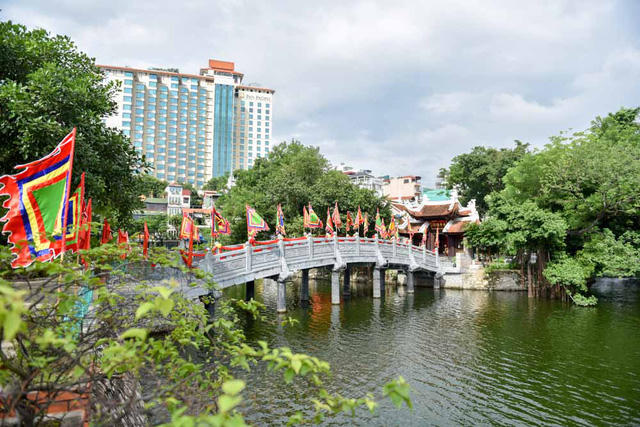 Đền được nối với bờ bằng cây cầu đá bắc qua mặt hồ Trúc Bạch. Cầu dài 18m gồm năm nhịp, mỗi nhịp dài 3,6m, rộng 2,25m.  Theo một tích xưa truyền lại, nơi đây từng có một di tích do vua Lý Công Uẩn cho xây để thờ cặp chó mẹ - chó con thành thần. Chó con khi sinh ra, trên lông có những đốm ghép lại thành chữ "Thiên tử" ứng với việc vua Lý Công Uẩn lên ngôi (vua Lý tuổi Tuất).