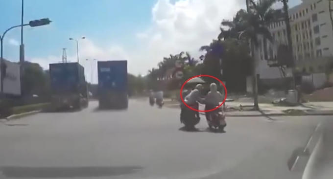 Hai tên cướp áp sát giật túi xách của cô gái.