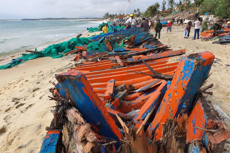 Tàu cá bị sóng đánh tan tác dọc bãi cát dài.