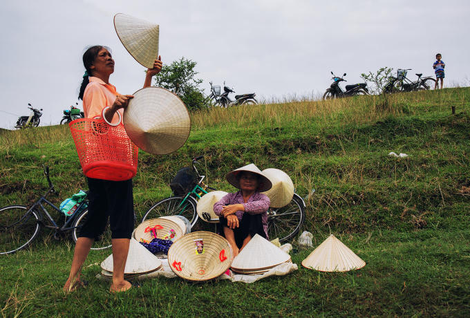 Ở hàng nón trên triền đê, người phụ nữ đang chọn cho mình một chiếc nón tốt nhất