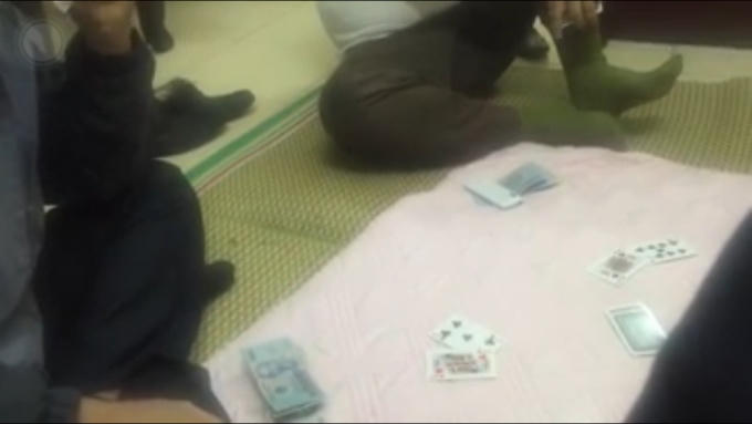 Đoạn clip quay lại được cảnh 4 người đàn ông ngồi đánh bạc trong trụ sở. (Ảnh: Cắt từ clip).