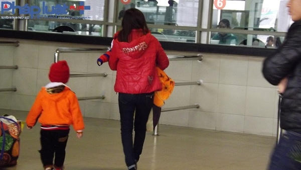 Bà mẹ trẻ và hai đứa con đang bồng bế nhau để làm thủ tục về quê ăn Tết.