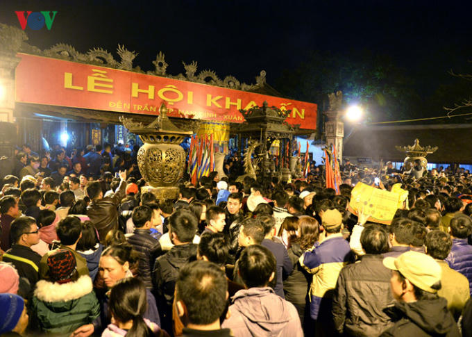 Sân đền toàn người và người san sát nhau, tay cầm lễ tiến vào đền.