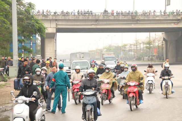 Rất đông người dân mặc áo mưa chờ sẵn tại nút giao quốc lộ 1 - quốc lộ 5.