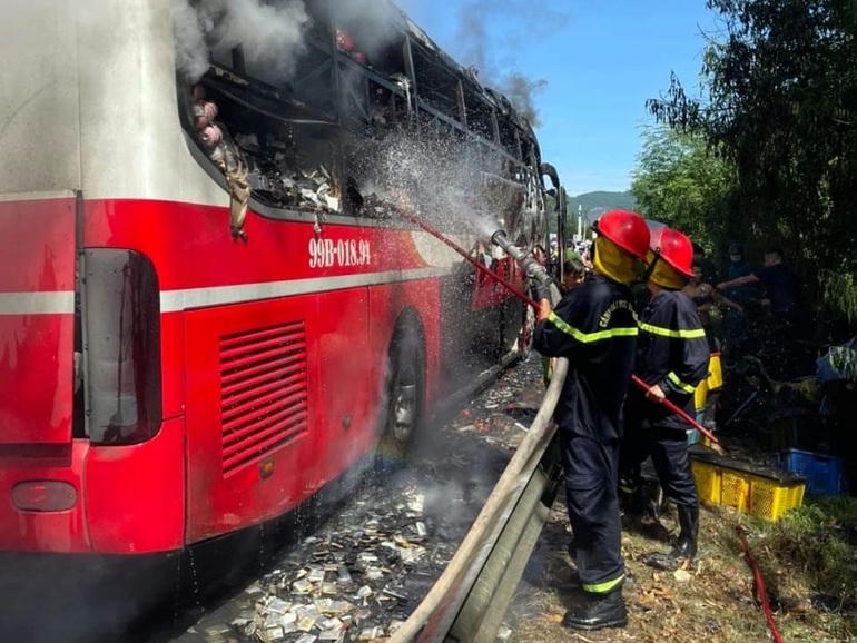 Lực lượng chức năng dập tắt ngọn lửa bao trùm chiếc xe khách (Ảnh: Cao Minh).