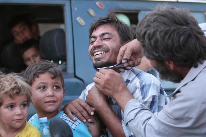 Một người đàn ông vui vẻ khi được cắt râu. Dưới sự cai trị của IS, nam giới buộc phải để râu, còn phụ nữ phải đeo mạng che mặt. (Ảnh: Reuters)