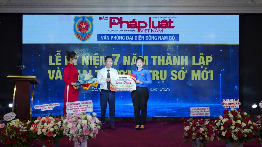 Ông Vũ Hoài Nam - Tổng Biên Tập Báo Pháp luật Việt Nam trao hoa và bảng vàng tặng 50 chiếc xe đạp trị cho đại diện tỉnh Bình Dương .