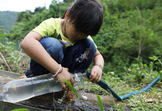 Bé Tâm Nhi (6 tuổi, con gái của chị Thái) lấy nước vào chai. Đây là nguồn nước sạch duy nhất được người dân dùng để uống và nấu cơm. Việc tắm, giặt, họ vẫn sử dụng nước sông Lam đục ngầu.