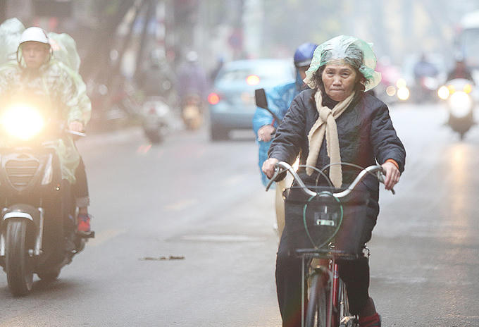 Một người phụ nữ đi xe đạp dùng túi ni lông đội lên đầu.