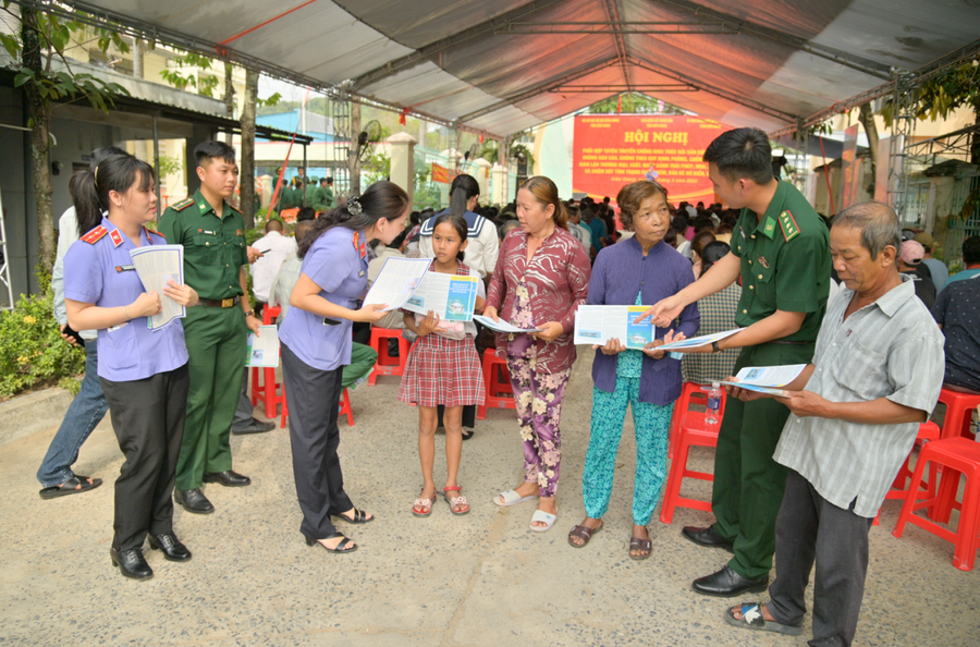 Cán bộ Biên phòng, Viện Kiểm sát tỉnh Kiên Giang hướng dẫn người dân tìm hiểu các nội dung trong tờ rơi về chống khai thác hải sản bất hợp pháp và các hành vi được xem là vi phạm pháp luật.