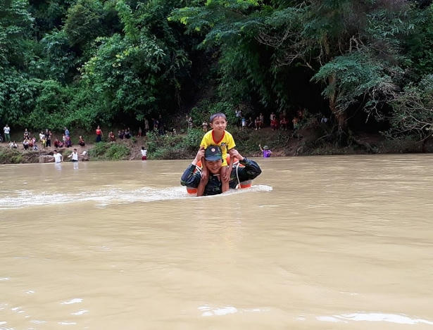 Cán bộ biên phòng và nụ cười trên môi khi kiệu các em học sinh vượt sông. (Ảnh: BĐBP Điện Biên)