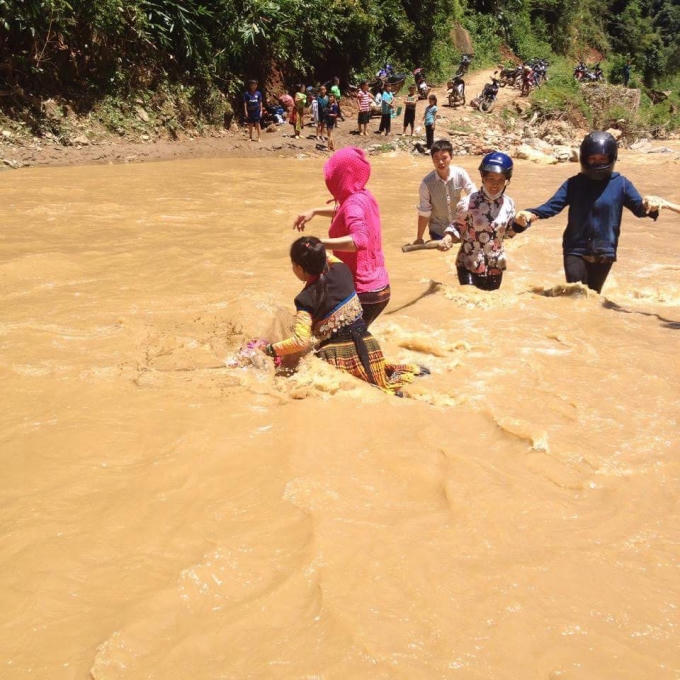 thày cô giáo và các em học sinh phải dìu dắt nhau qua những con suối dữ.