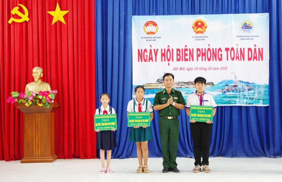 Thiếu tá Lâm Huy Vũ - Chính trị viên Đồn Biên phòng Cửa khẩu cảng Năm Căn tặng học bổng cho các em học sinh trong chương trình “Nâng bước em đến trường” của đơn vị nhận đỡ đầu.