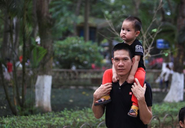 Một phụ huynh kiệu con nhỏ trên vai khi đi tham quan vườn bách thú.