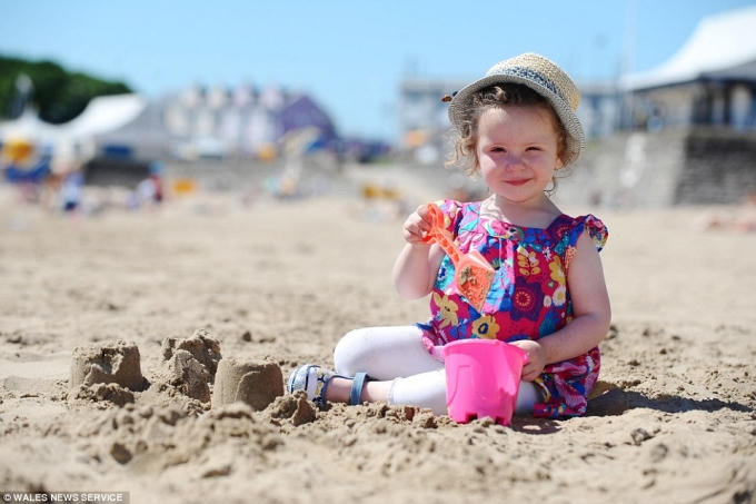 Một em bé được bố mẹ cho ra bãi biển tránh nóng. (Ảnh: Daily Mail)