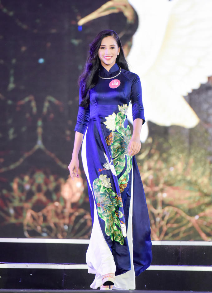 Trần Tiểu Vy thướt tha trong phần thi áo dài với trang phục họa tiết hoa sen nổi bật của nhà thiết kế Lan Hương, trên sân khấu thi chung khảo ở Nghệ An. So với những thí sinh cùng độ tuổi 18, vừa tốt nghiệp THPT, nhan sắc của Tiểu Vy được nhận xét chín muồi hơn.