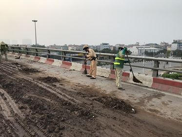 Cán bộ, chiến sĩ CSGT phối hợp với đơn vị môi trường quét dọn bùn đất rơi vãi.