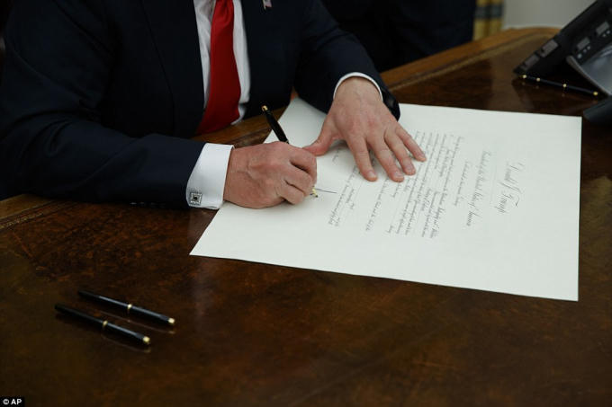 Tại đây, ông thực hiện quyết định đầu tiên khi ký bãi bỏ đạo luật Obamacare - một trong những di sản còn lại từ thời ông Obama. (Ảnh: AP)