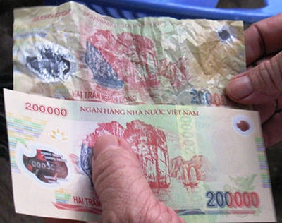 Tiền thật (dưới), tiền giả (trên) (Ảnh: Ngọc Toàn).