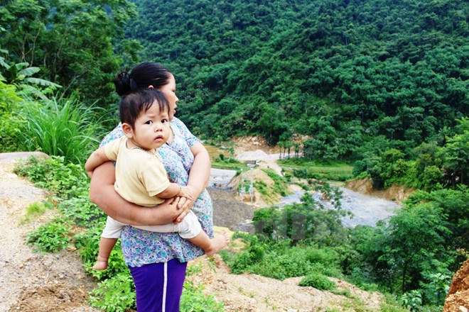 Người dân xóm Khướng, xã Tự Do, huyện Lạc Sơn, tỉnh Hòa Bình đứng bên công trình xây nhà máy thủy điện ngay dưới chân Thác Mu. (Ảnh: Hùng Võ/Vietnam+)