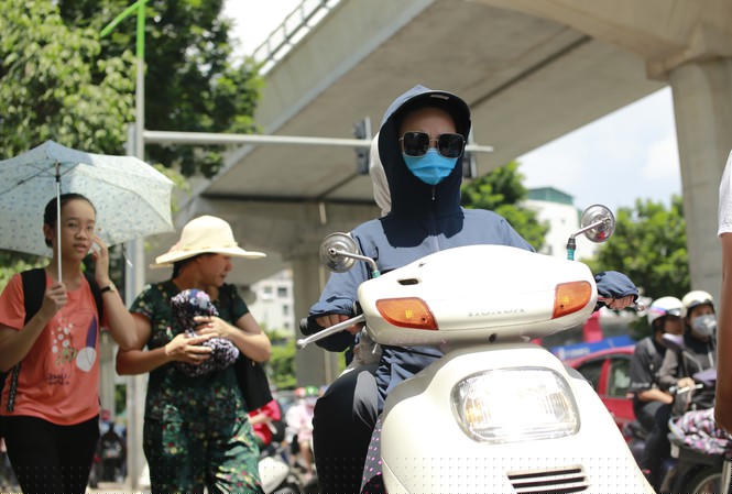 Người dân chống nắng bằng trang phục kín khi đi trên đường Xuân Thủy, Cầu Giấy, Hà Nội chiều 15/7 Ảnh: như ý